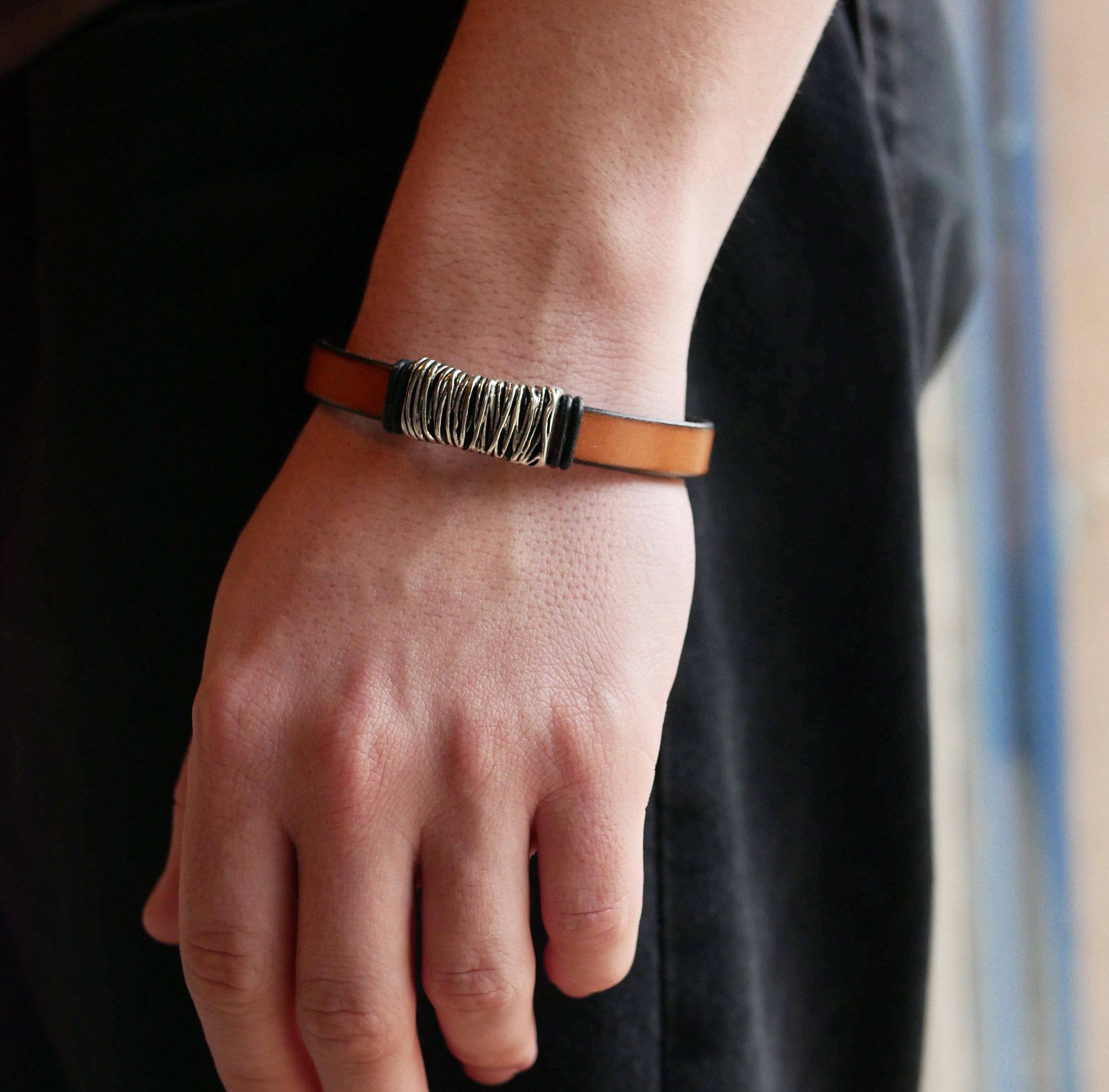 Bracelete em pele camel com decoração em metal entrançado e fecho em forma de T