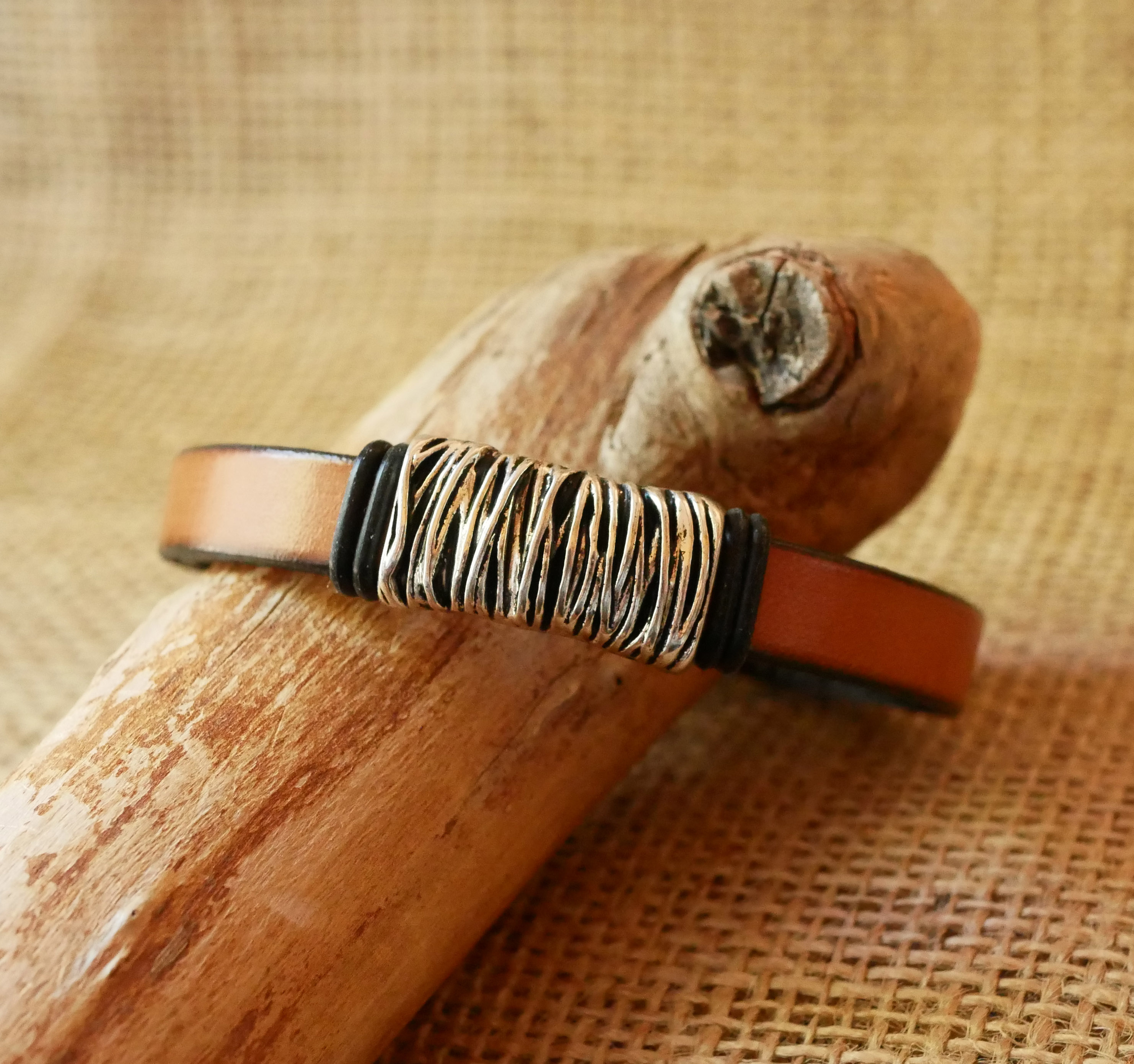 Bracelete em pele camel com decoração em metal entrançado e fecho em forma de T