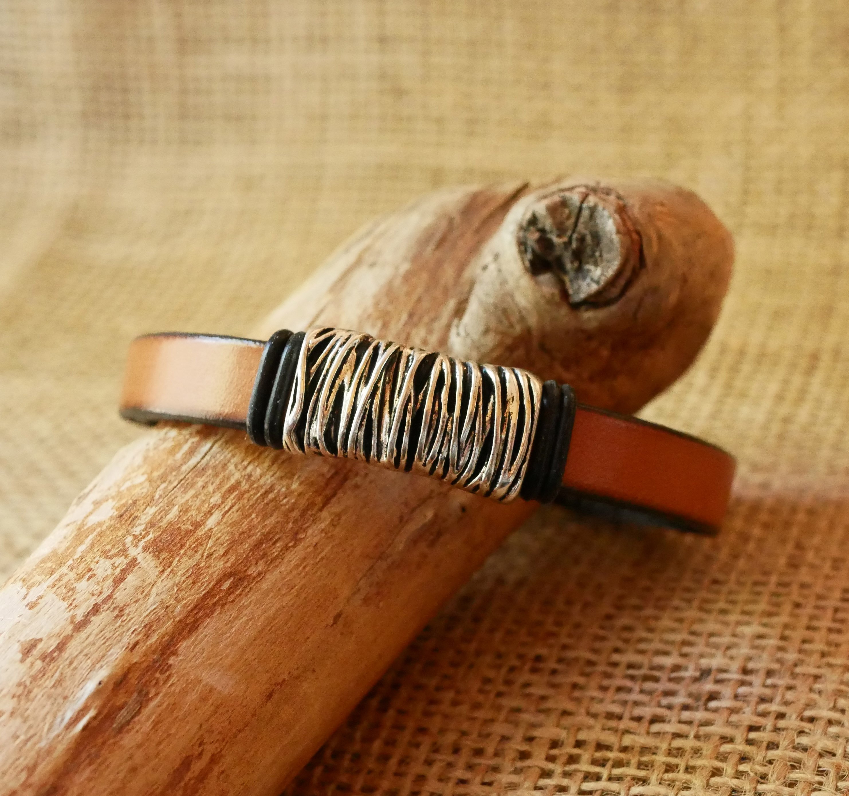 Bracelete em pele camel com decoração em metal entrançado e fecho em forma de T