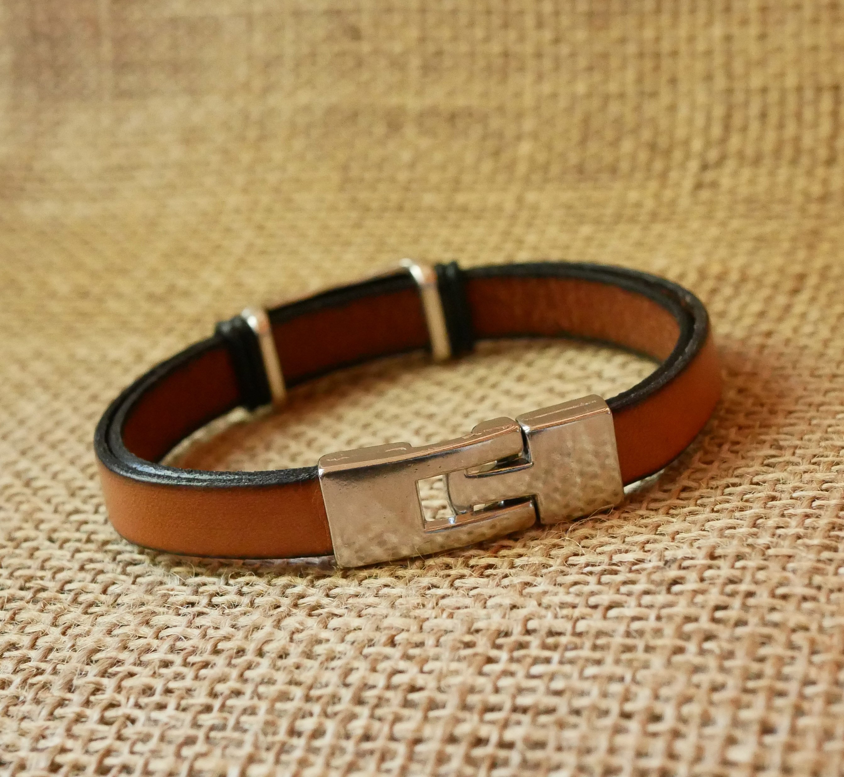 Bracelete em pele camel com decoração em metal entrançado e fecho em forma de T