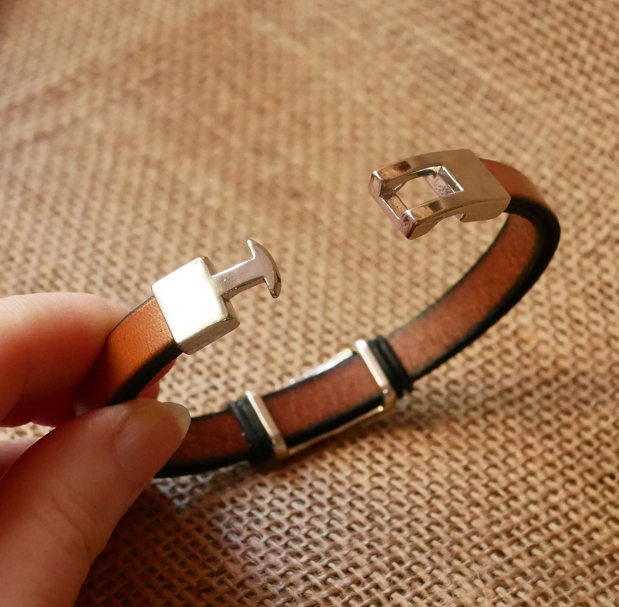 Bracelete em pele camel com decoração em metal entrançado e fecho em forma de T