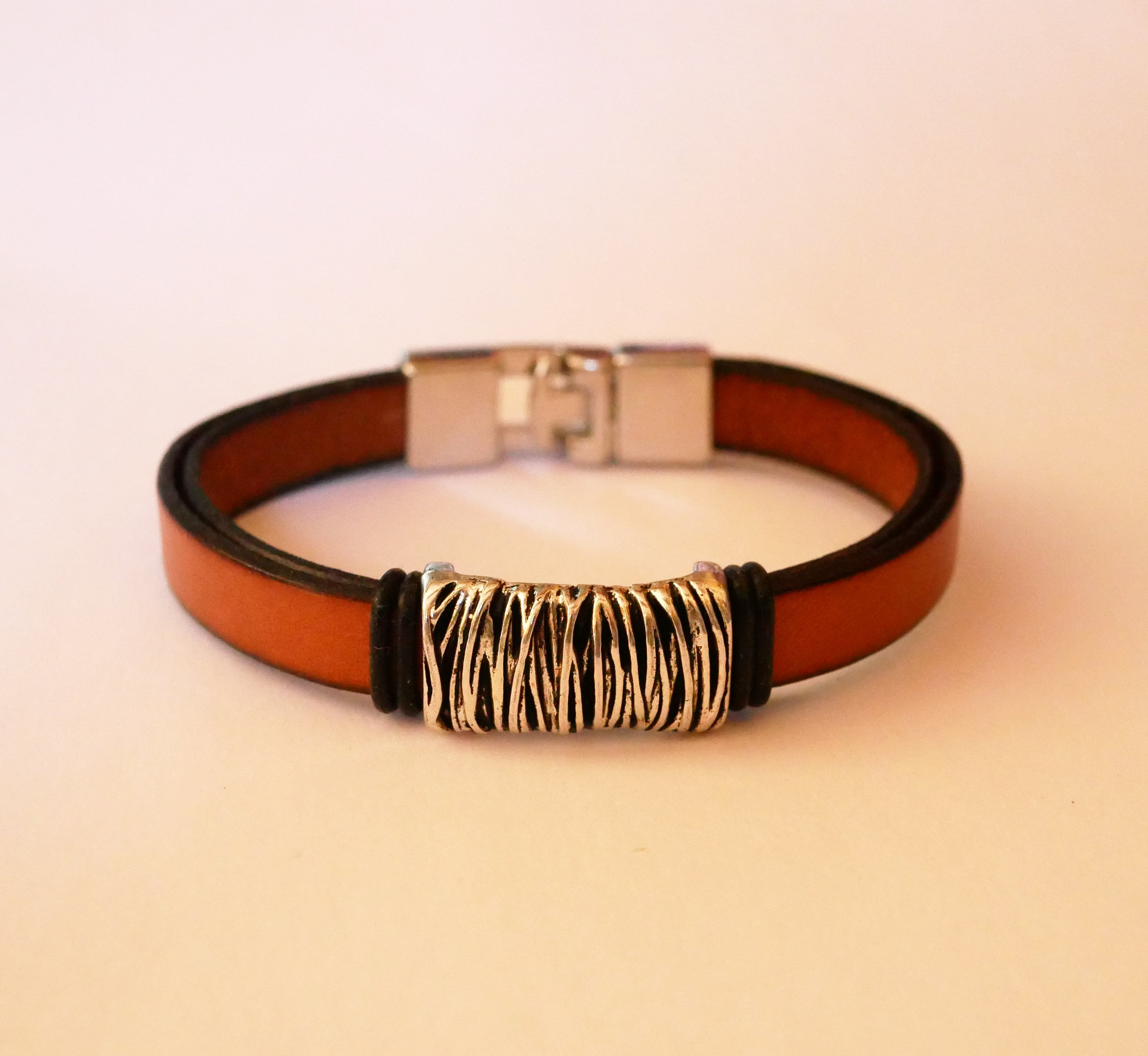 Bracelete em pele camel com decoração em metal entrançado e fecho em forma de T