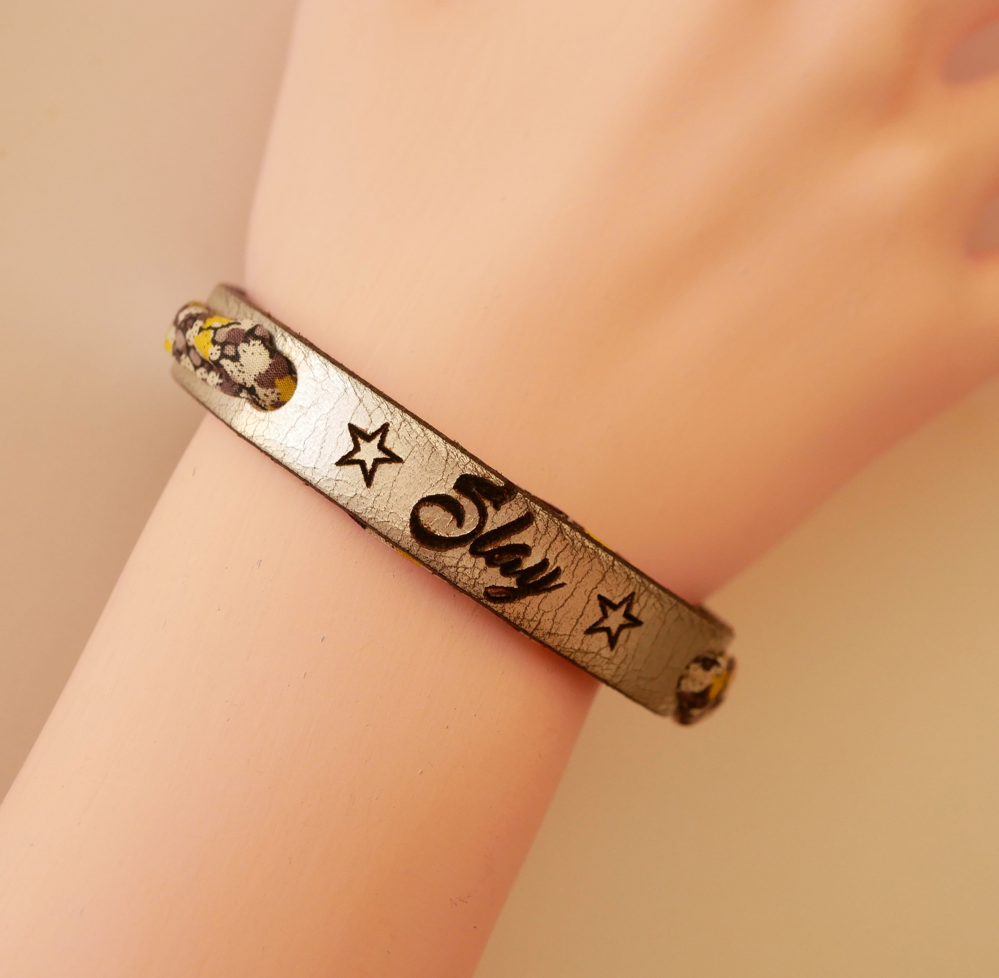 Pulseira Florâme gravada com flores amarelas em fita liberty em pele prateada