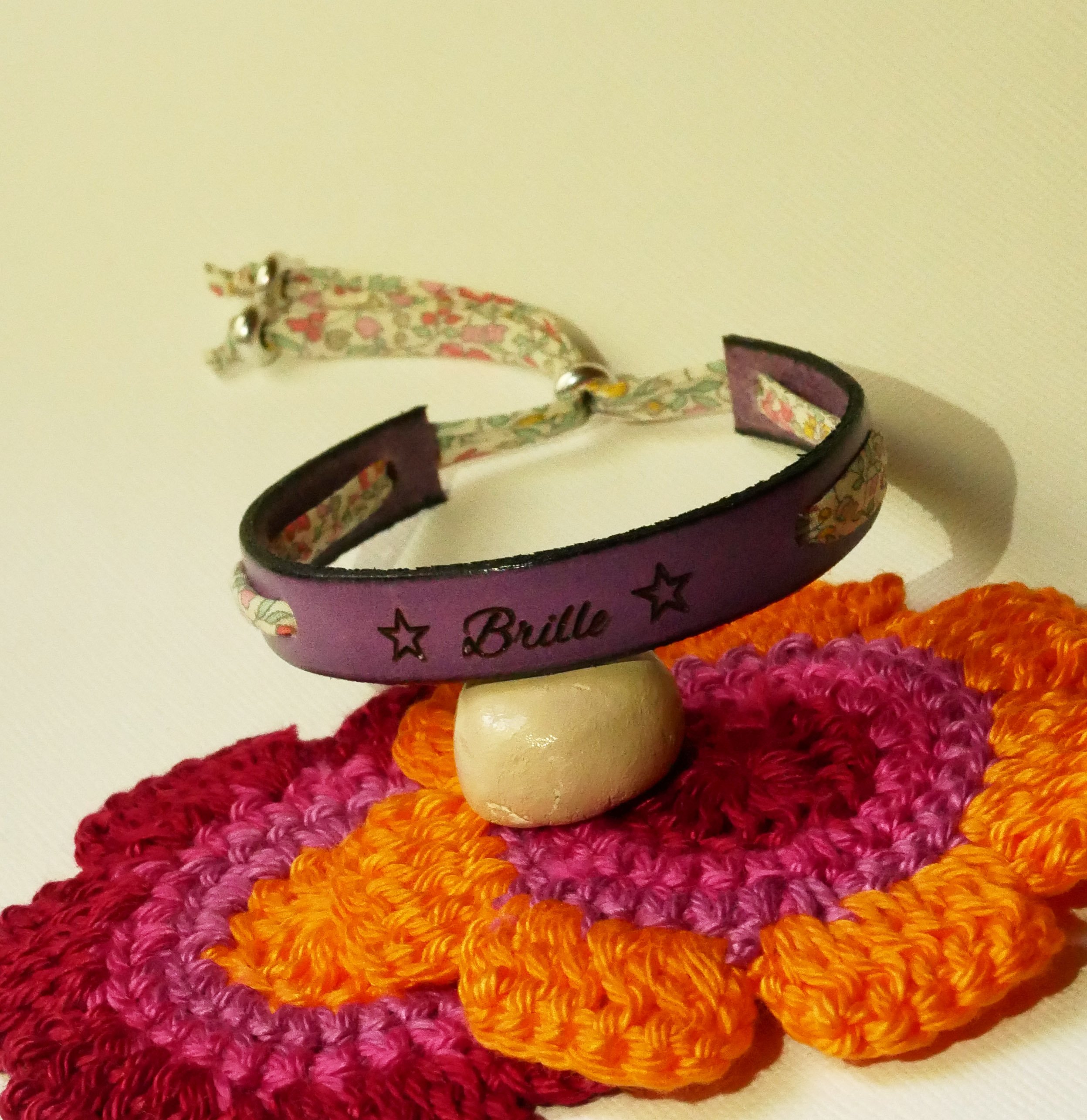 Pulseira Florâme "Brille" gravada com fita liberty em tons pastel sobre pele roxa