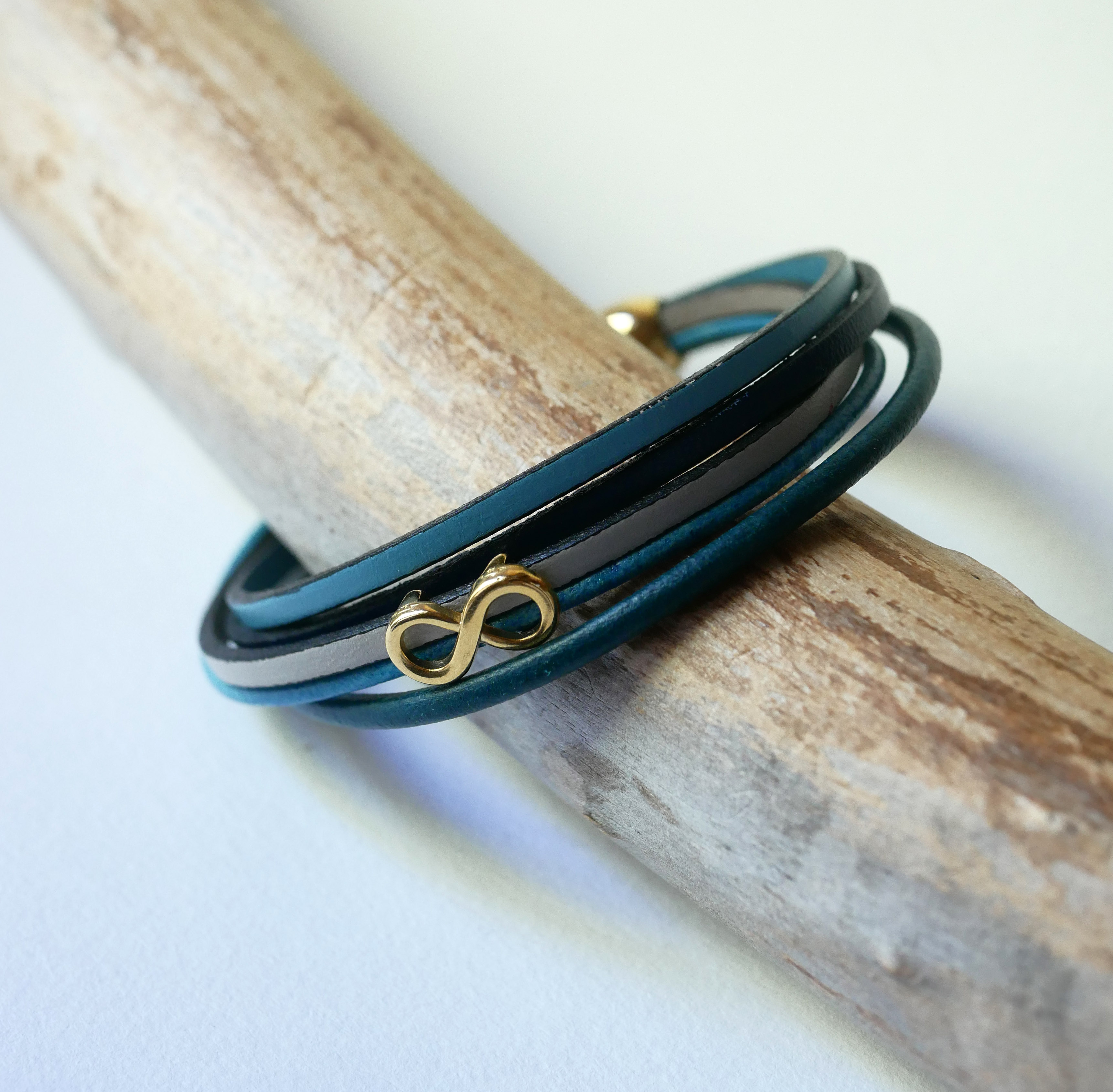 Pulseira com vários elos em pele azulada com motivo infinito dourado