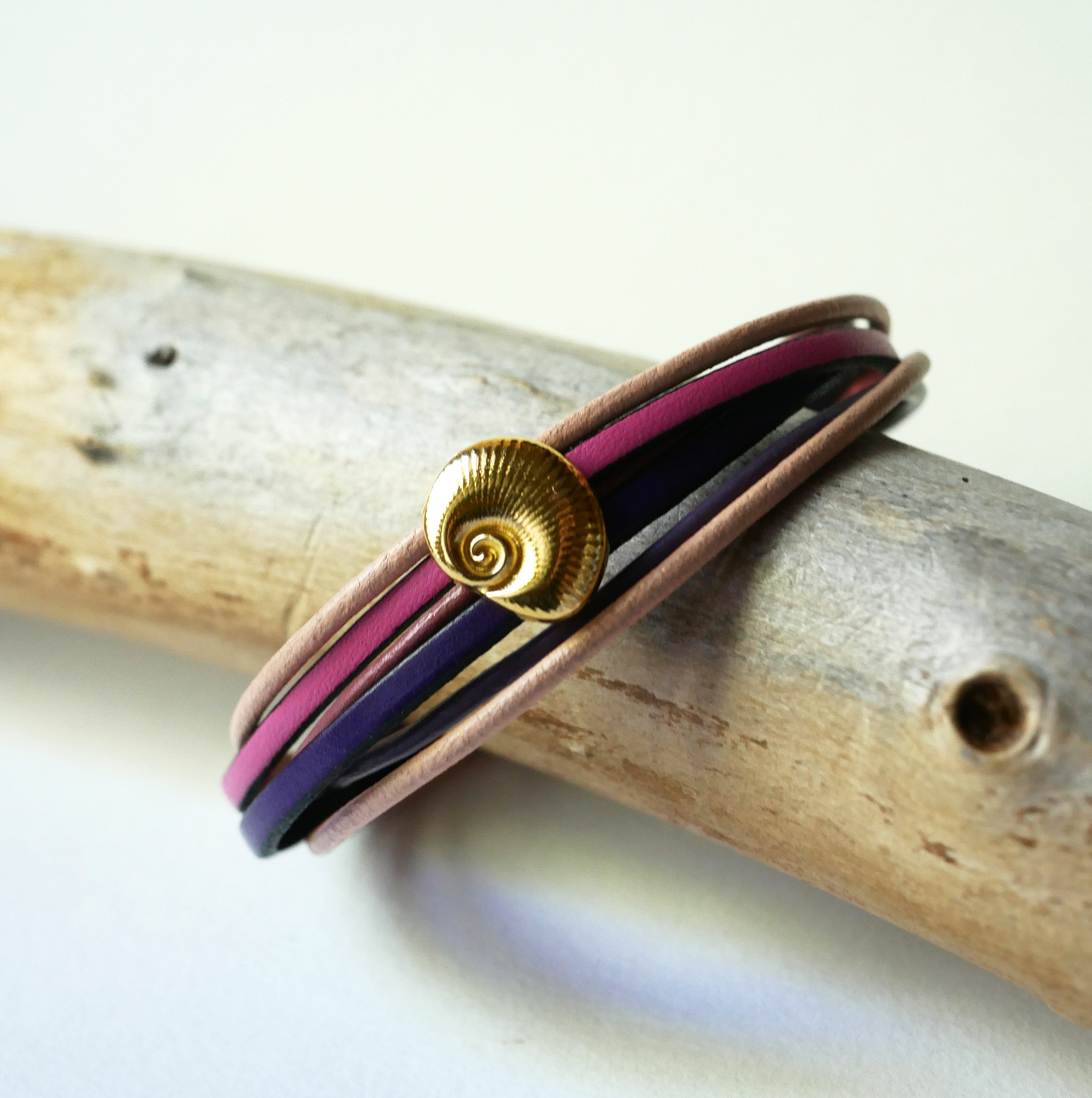 Pulseira com v&aacute;rios elos em pele de p&ecirc;ssego e malva com decora&ccedil;&atilde;o de conchas douradas