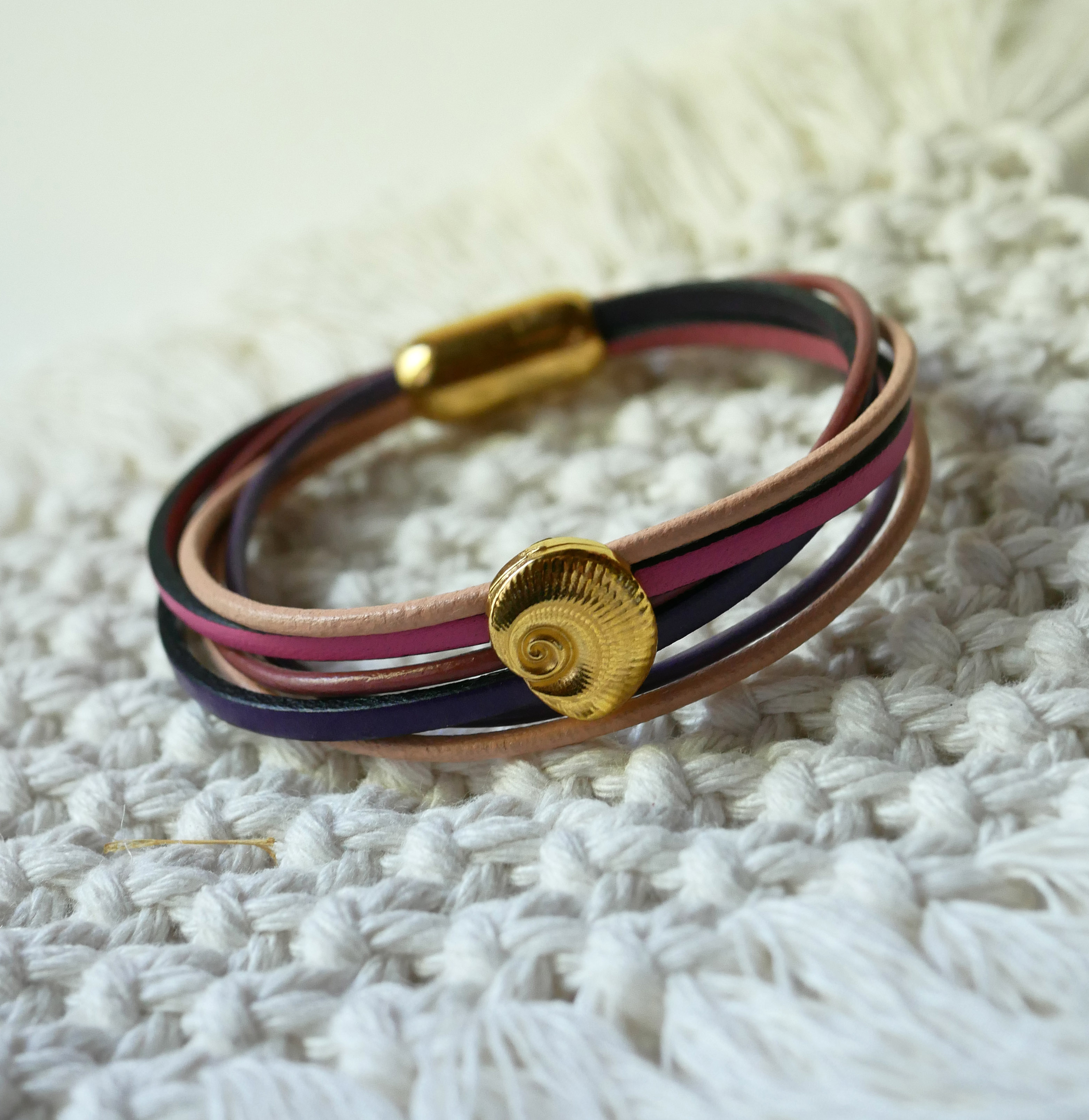 Pulseira com vários elos em pele de pêssego e malva com decoração de conchas douradas