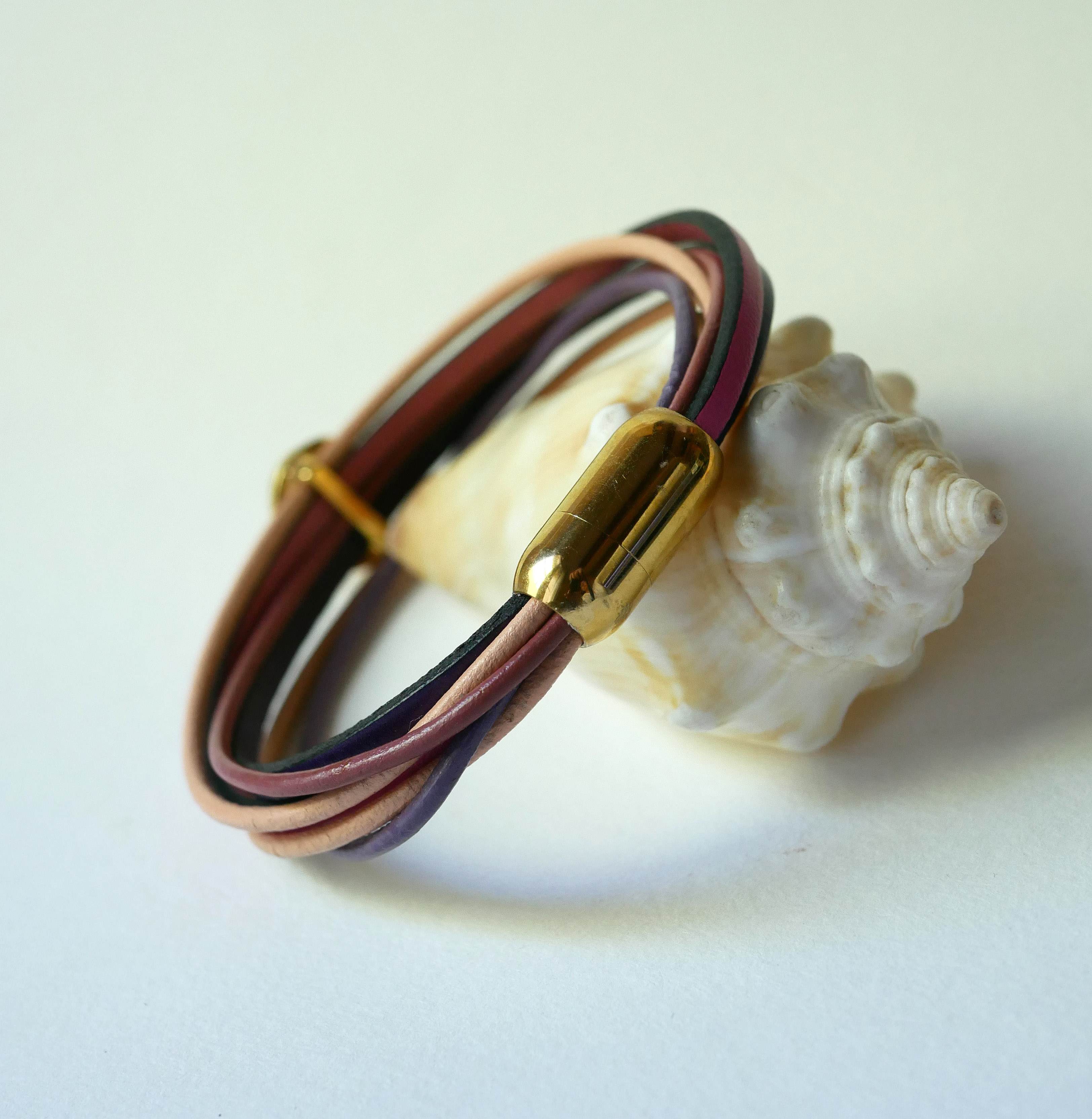 Pulseira com vários elos em pele de pêssego e malva com decoração de conchas douradas