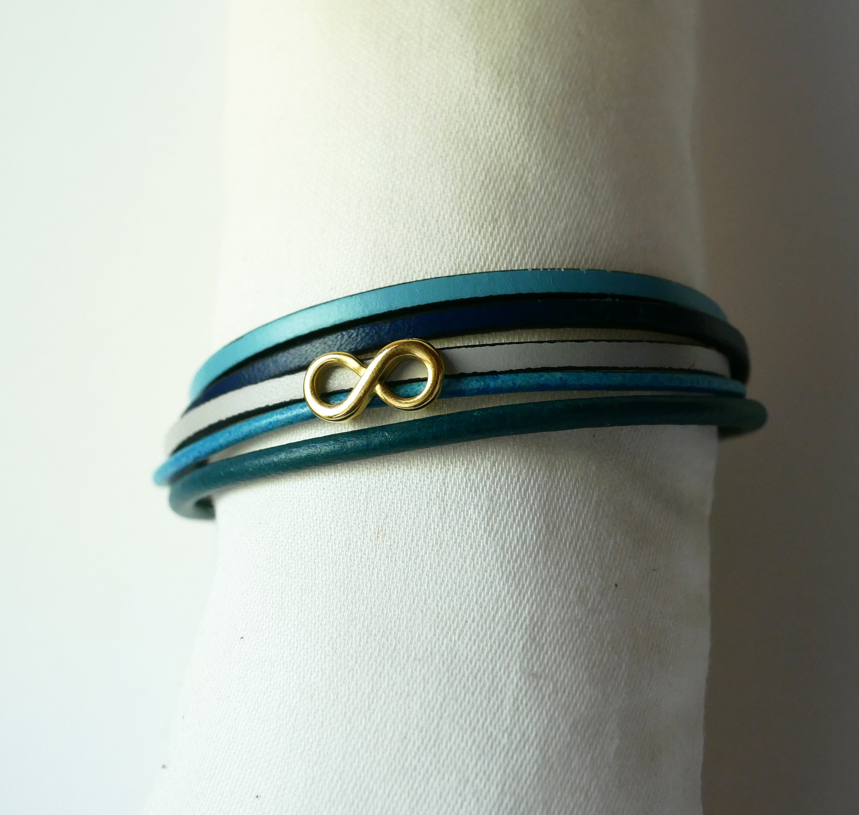 Pulseira com vários elos em pele azulada com motivo infinito dourado
