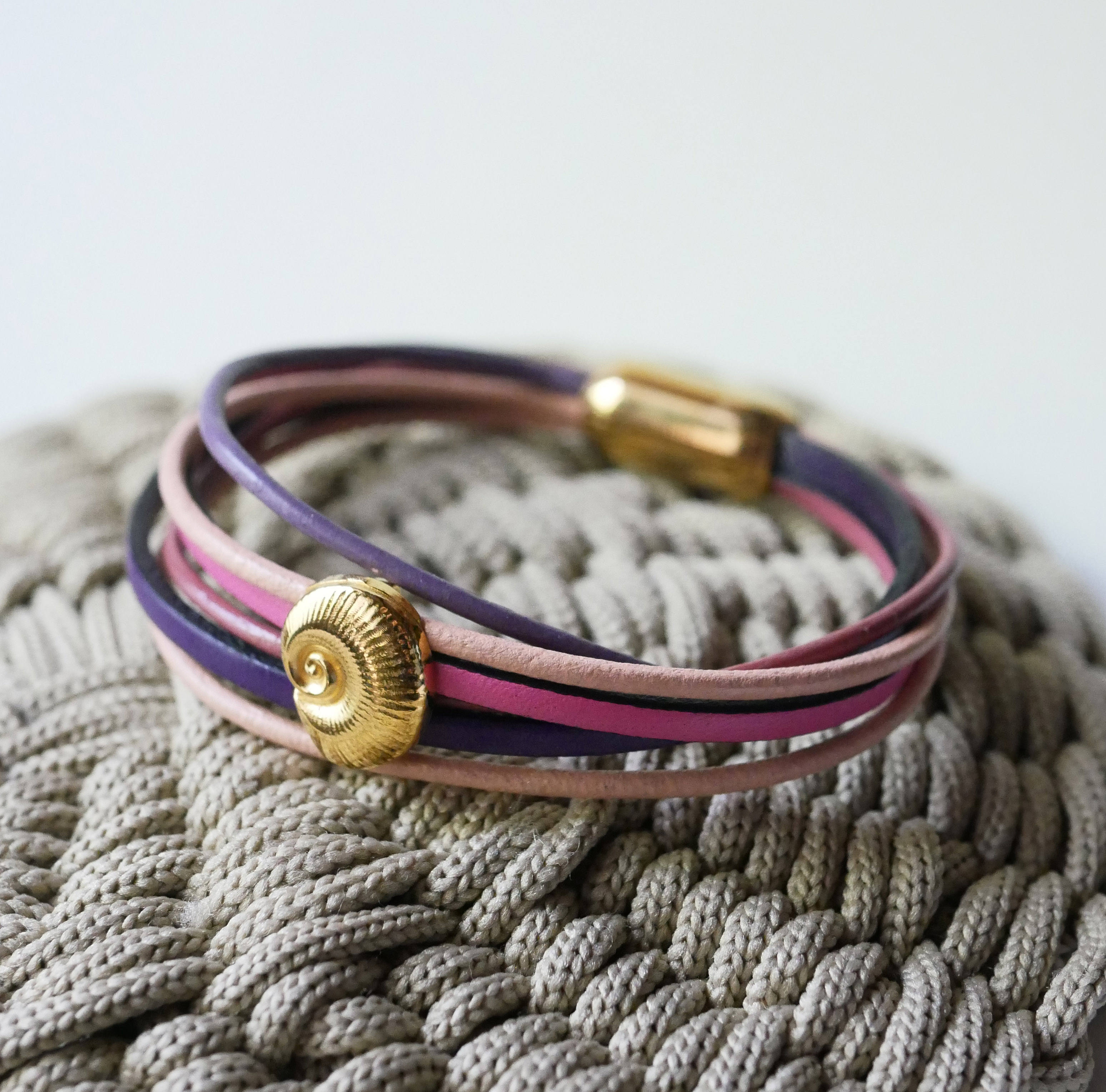 Pulseira com vários elos em pele de pêssego e malva com decoração de conchas douradas