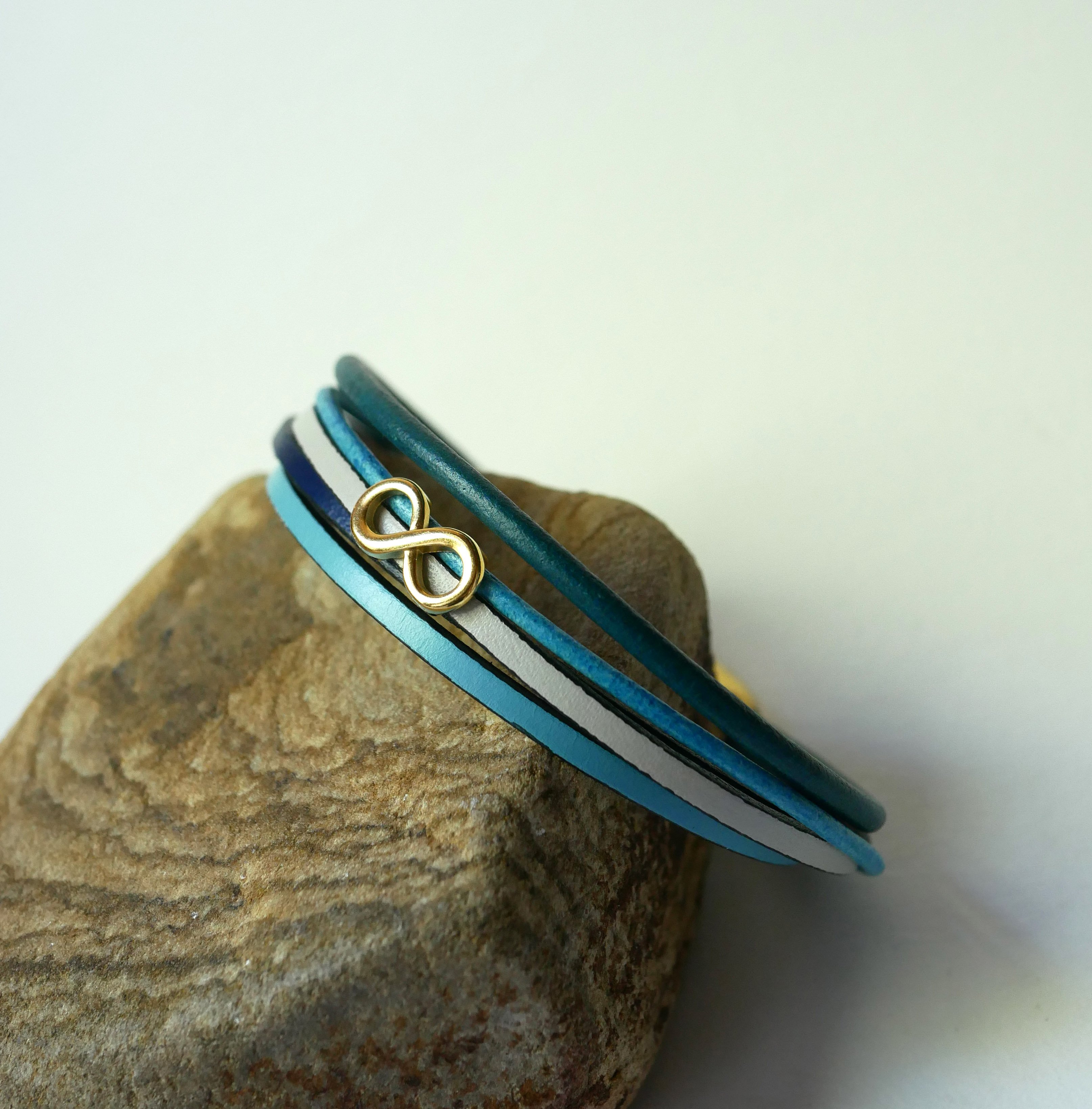 Pulseira com vários elos em pele azulada com motivo infinito dourado