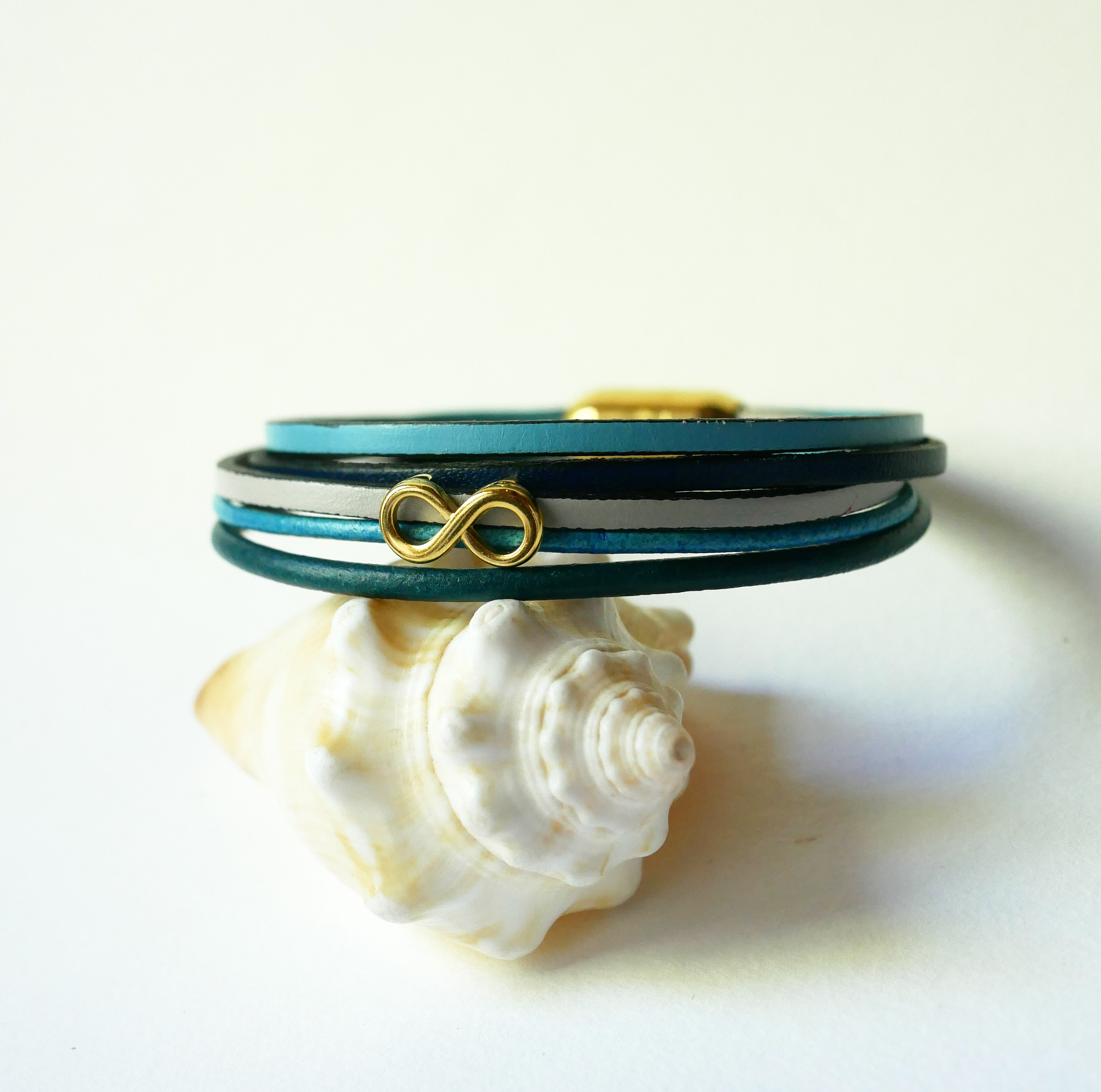 Pulseira com vários elos em pele azulada com motivo infinito dourado