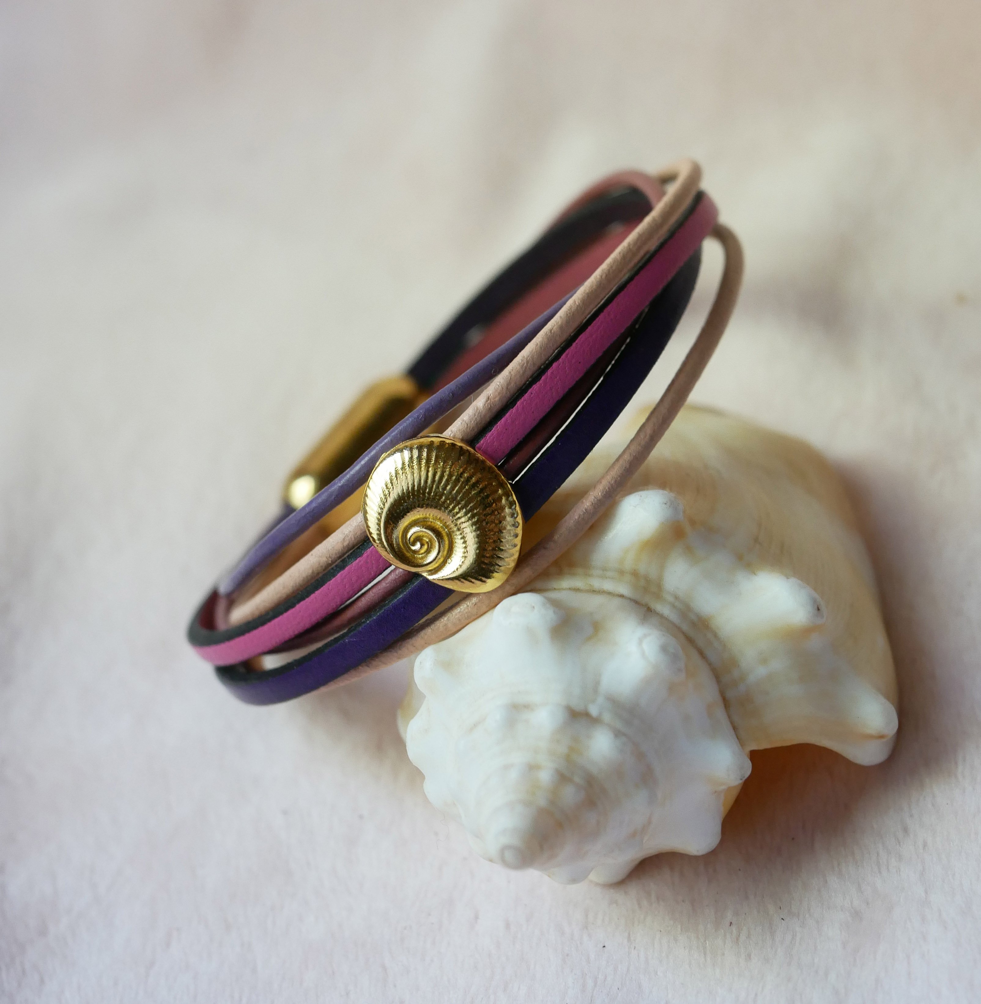 Pulseira com vários elos em pele de pêssego e malva com decoração de conchas douradas
