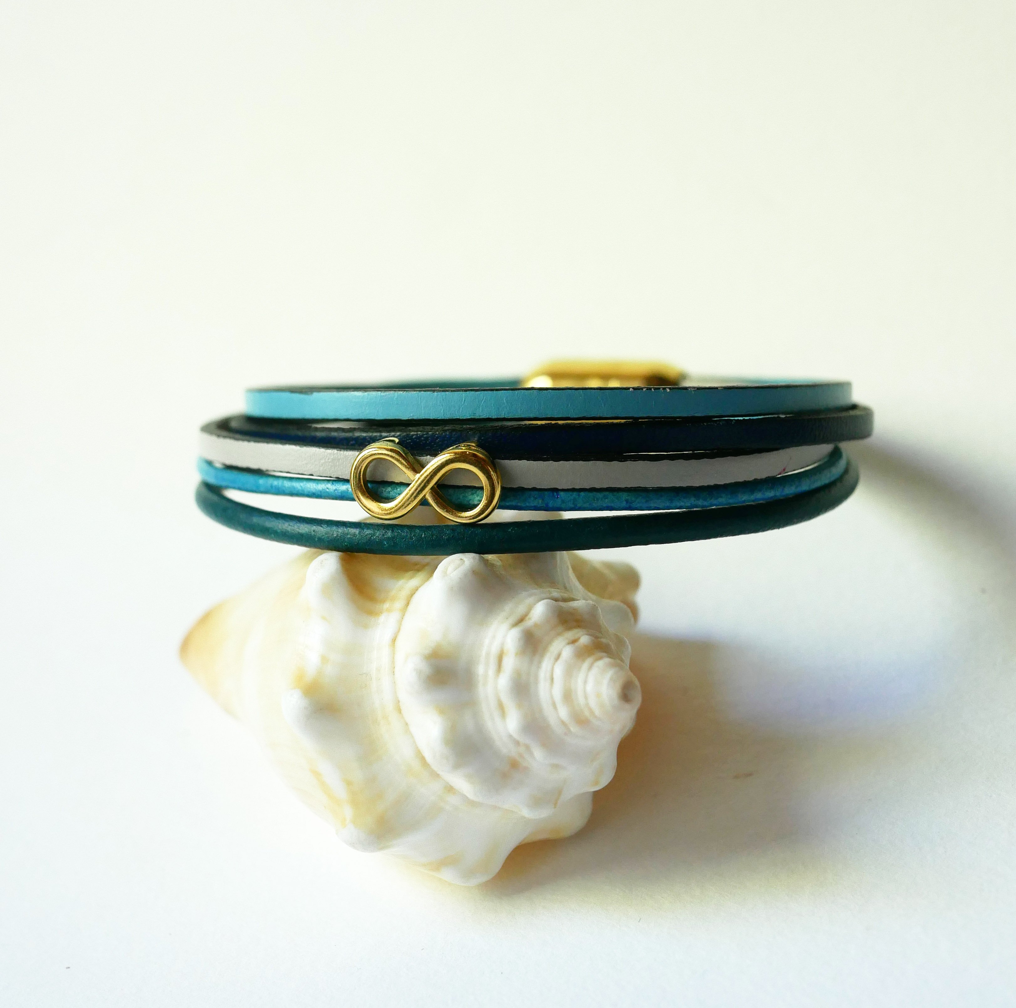 Pulseira com vários elos em pele azulada com motivo infinito dourado