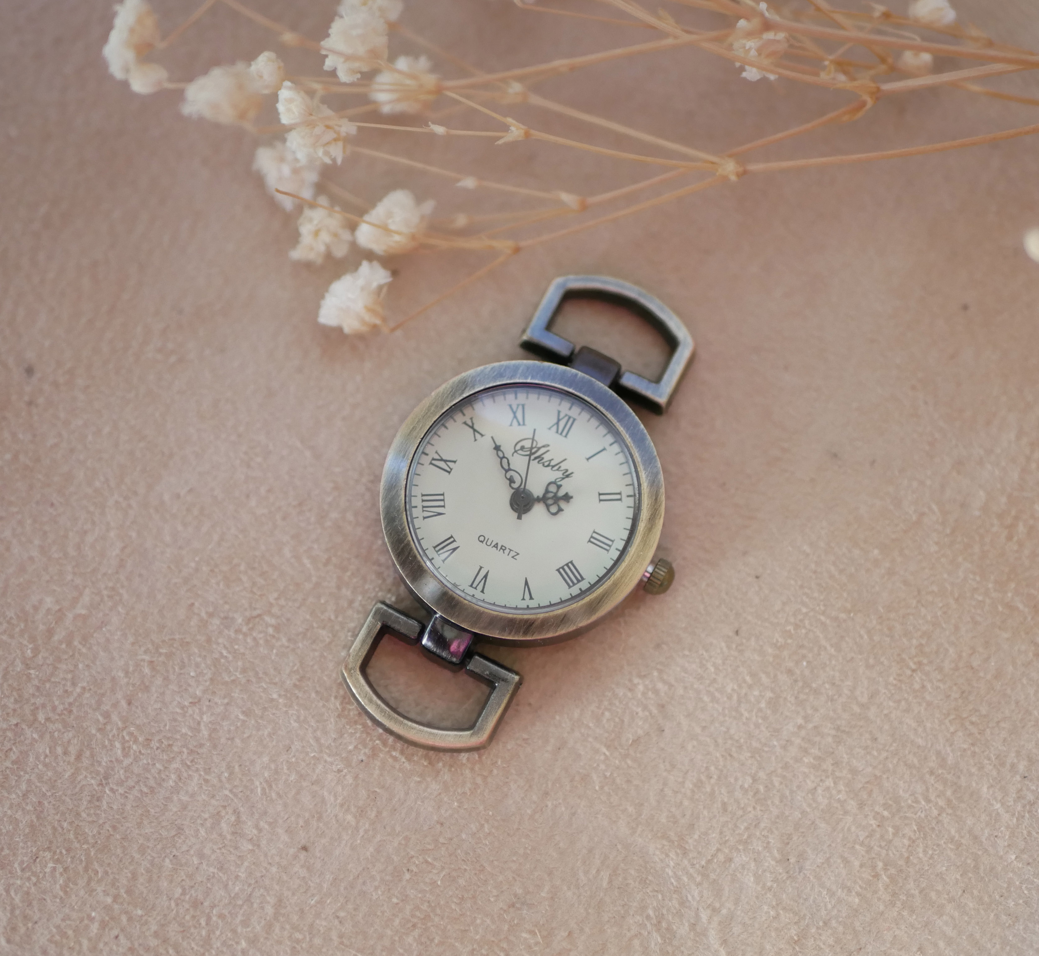 Cadran de montre vintage en bronze avec chiffres romains.