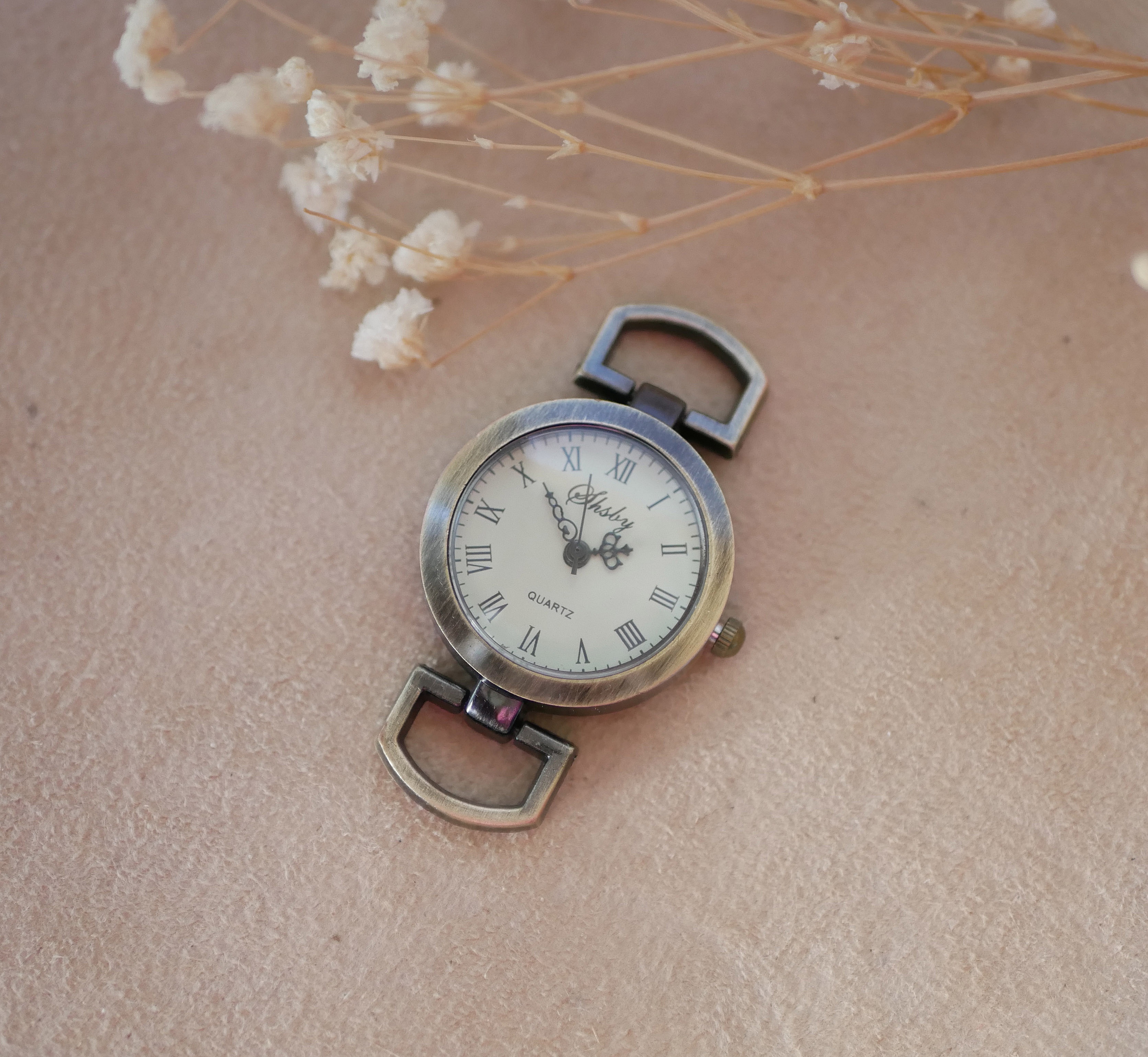 Cadran de montre vintage en bronze avec chiffres romains.