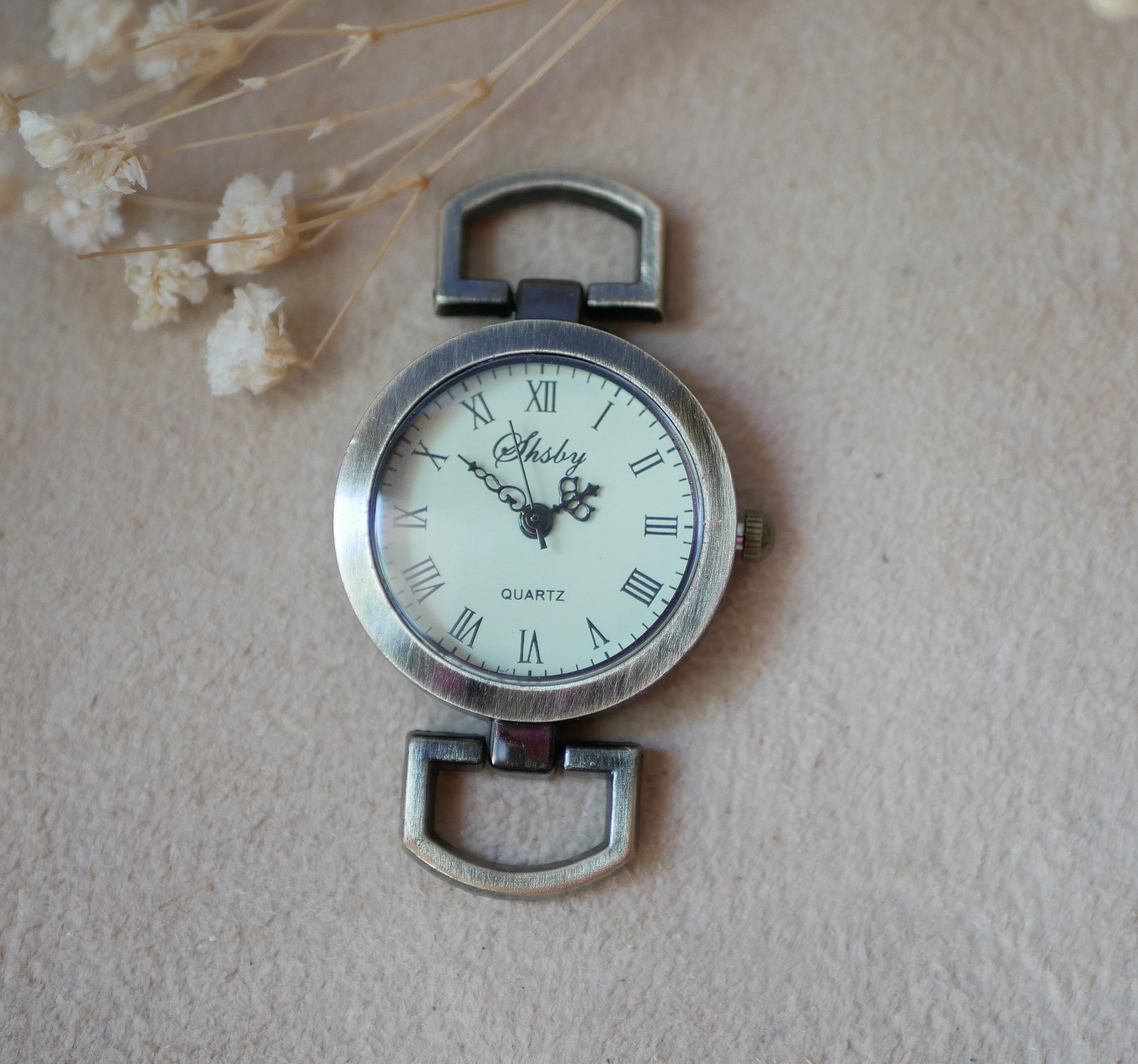 Cadran de montre vintage en bronze avec chiffres romains.