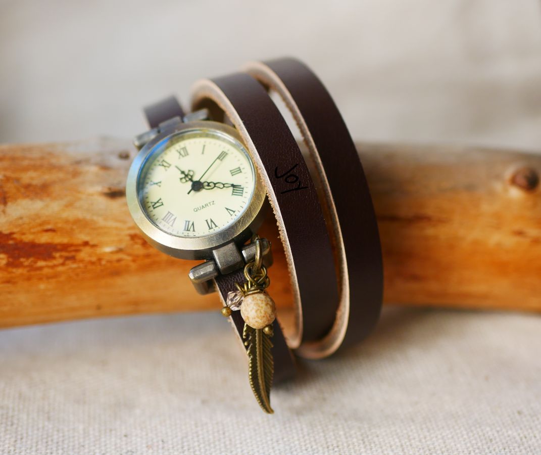 Relógio bracelete de couro com encantos de penas e pérolas