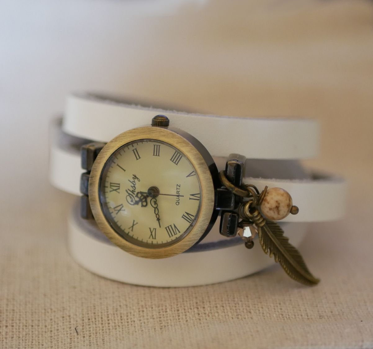 Relógio bracelete de couro com encantos de penas e pérolas