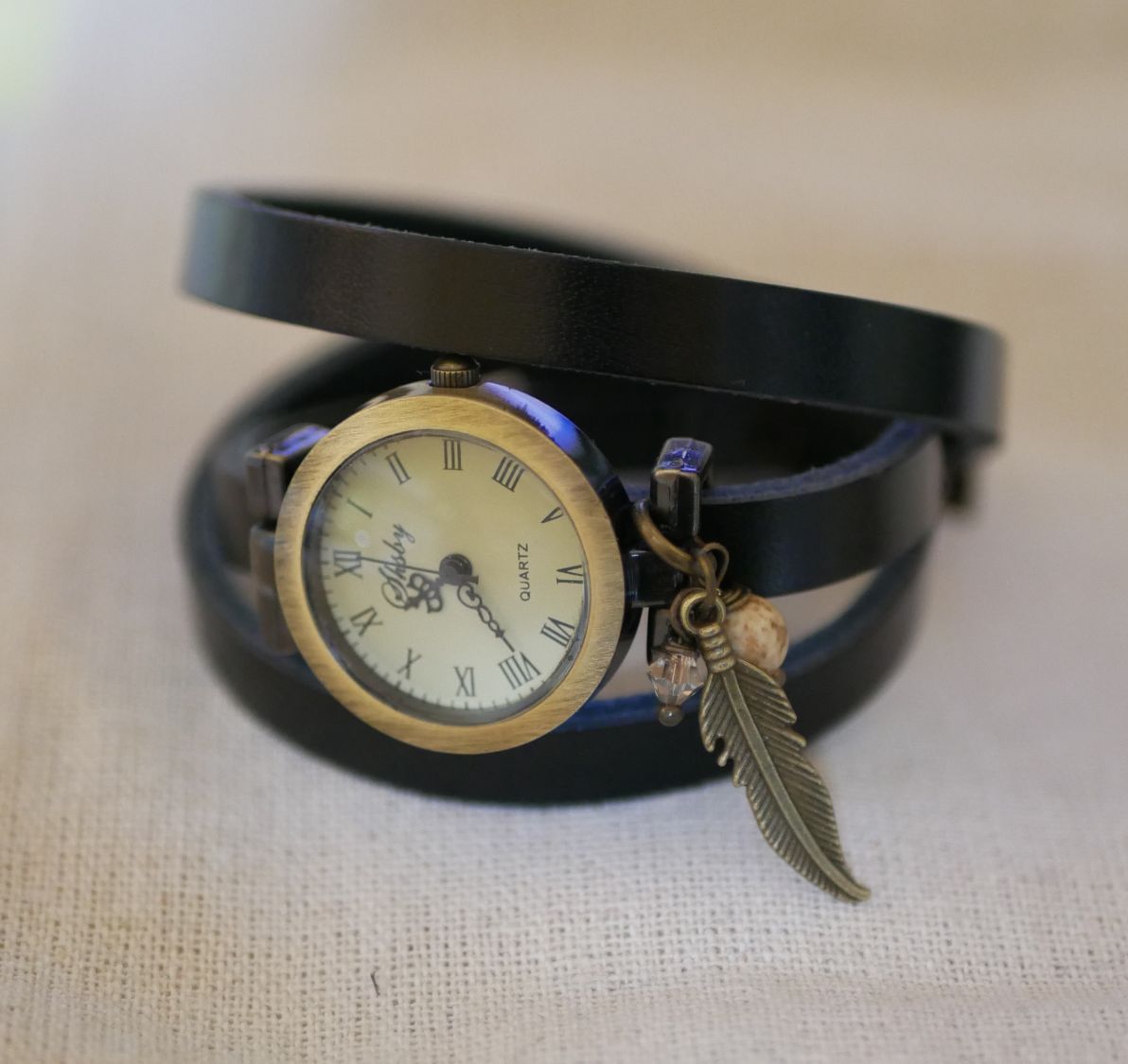 Relógio bracelete de couro com encantos de penas e pérolas