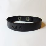 Bracelete em pele mista preta gravada com botões de pressão