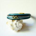 Pulseira com vários elos em pele azulada com motivo infinito dourado